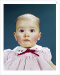 1960s Portrait Baby Girl Silly Facial Expression Red Bow At Collar Looking At Camera by Anonymous