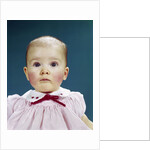 1960s Portrait Baby Girl Silly Facial Expression Red Bow At Collar Looking At Camera by Anonymous