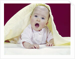 1960s Baby Mouth Wide Open Peeking Out From Under Yellow Blanket Looking At Camera by Anonymous