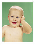 1960s Smiling Happy Baby Looking Off To The Side With Hand Touching Face by Anonymous