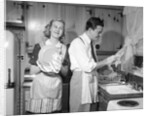 1950s smiling couple washing the dishes together by Anonymous