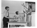 1940s housewife in kitchen showing plucked turkey to children by Anonymous