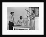 1940s housewife in kitchen showing plucked turkey to children by Anonymous