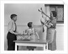 1940s housewife in kitchen showing plucked turkey to children by Anonymous
