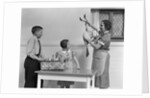 1940s housewife in kitchen showing plucked turkey to children by Anonymous