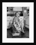 1960s smiling housewife sitting on full laundry basket by Anonymous