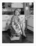 1960s smiling housewife sitting on full laundry basket by Anonymous
