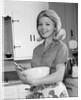 1960s 1970s smiling blond housewife in kitchen holding mixing bowl by Anonymous