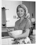 1960s 1970s smiling blond housewife in kitchen holding mixing bowl by Anonymous