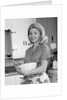 1960s 1970s smiling blond housewife in kitchen holding mixing bowl by Anonymous