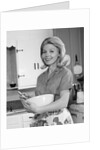 1960s 1970s smiling blond housewife in kitchen holding mixing bowl by Anonymous