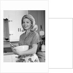 1960s 1970s smiling blond housewife in kitchen holding mixing bowl by Anonymous