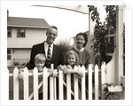 1950s family of four behind picket fence by Anonymous