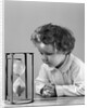 1940s young girl leaning on table staring at hourglass by Anonymous