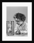 1940s young girl leaning on table staring at hourglass by Anonymous