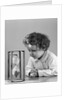 1940s young girl leaning on table staring at hourglass by Anonymous