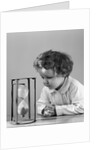 1940s young girl leaning on table staring at hourglass by Anonymous