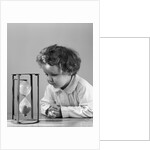 1940s young girl leaning on table staring at hourglass by Anonymous