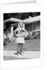 1950s girl on suburban sidewalk playing with a hula hoop by Anonymous