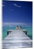 couple Sitting On A Pier In An Ocean Lagoon by Anonymous