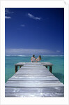 couple Sitting On A Pier In An Ocean Lagoon by Anonymous