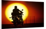 1980s silhouette of anonymous man on motorcycle driving toward rising setting sun by Anonymous