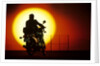1980s silhouette of anonymous man on motorcycle driving toward rising setting sun by Anonymous