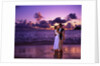 Dressed up couple embracing on the beach at sunset by Anonymous