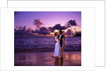 Dressed up couple embracing on the beach at sunset by Anonymous