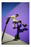 Boy Wearing Roller Blades Jumping Against Wall by Anonymous