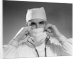 1960s male doctor wearing surgical mask and operating room scrubs by Anonymous