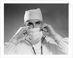 1960s male doctor wearing surgical mask and operating room scrubs by Anonymous
