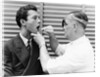 1930s 1940s doctor examining throat of a young man by Anonymous
