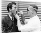 1930s 1940s doctor examining throat of a young man by Anonymous