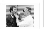 1930s 1940s doctor examining throat of a young man by Anonymous
