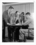 1950s group of businessmen looking at a blueprint on a table by Anonymous