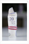 A roll of twenty pound notes on a table by Anonymous