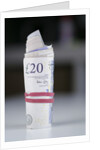 A roll of twenty pound notes on a table by Anonymous