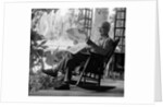 1970s elderly man reading newspaper on porch in a rocker by Anonymous