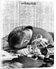 1930s man with head on his desk holding stock ticker tape by Anonymous