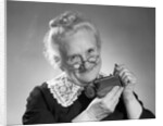 1950s portrait of senior woman putting change into a purse by Anonymous