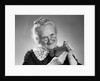 1950s portrait of senior woman putting change into a purse by Anonymous