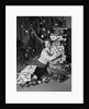 1950s portrait of young woman holding stack of presents next to a Christmas tree by Anonymous