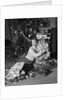 1950s portrait of young woman holding stack of presents next to a Christmas tree by Anonymous