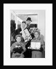 1960s family standing in doorway wearing winter coats and holding Christmas presents by Anonymous