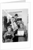 1960s family standing in doorway wearing winter coats and holding Christmas presents by Anonymous