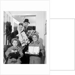 1960s family standing in doorway wearing winter coats and holding Christmas presents by Anonymous