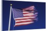 American Flag is blurred with the motion of the wind against the blue sky by Anonymous