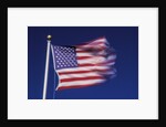 American Flag is blurred with the motion of the wind against the blue sky by Anonymous