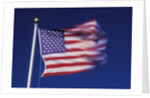 American Flag is blurred with the motion of the wind against the blue sky by Anonymous